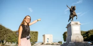 visite guidee montpellier depuis aeroport avec touriste devant statue